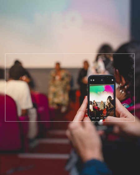An audience member photographs a conversation from their seat