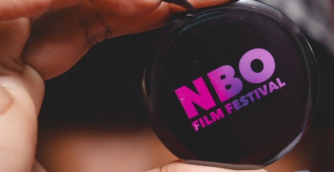 Hands holding a round NBO Film Festival badge